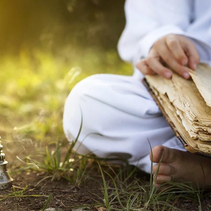 Yogi sitzt auf dem Gras und liest ein Buch über Ayurveda