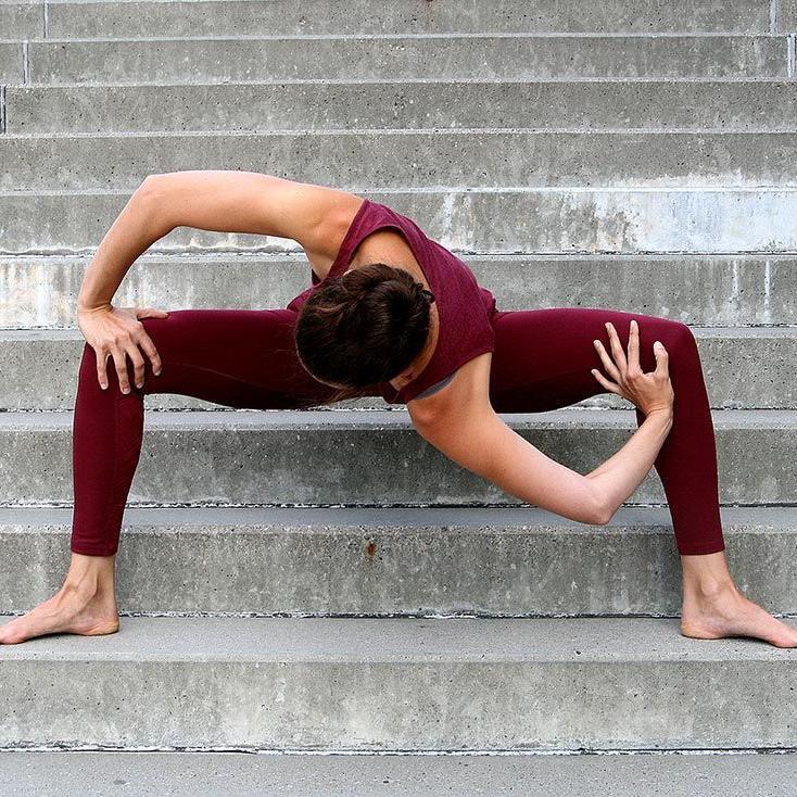 Frau steht auf Treppenstufen und führt eine Yogapose aus, dies ist gut für die Faszien