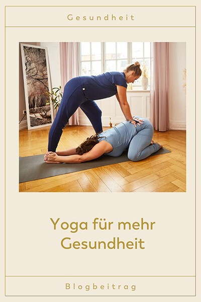 Eine Yogalehrerin hilft einer Yogini